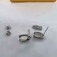 A pair of silver-tone Coach D-ring earrings shown disassembled on a white surface, with the small matching stud backs and a small rectangular box engraved with the Coach logo.