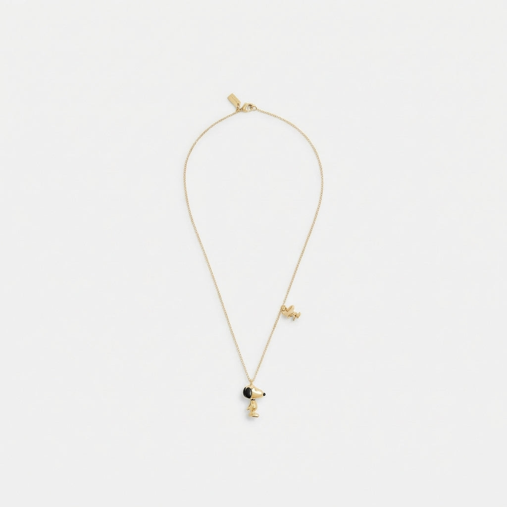 A delicate gold chain necklace featuring a small character pendant with a black circular accent, displayed against a clean white background.