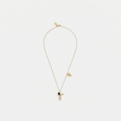 A delicate gold chain necklace featuring a small character pendant with a black circular accent, displayed against a clean white background.