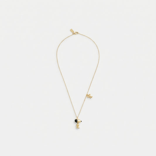 A delicate gold chain necklace featuring a small character pendant with a black circular accent, displayed against a clean white background.