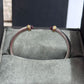 Silver bracelet with gold accents on a gray cushioned surface