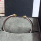 Silver bracelet with gold accents on a gray surface