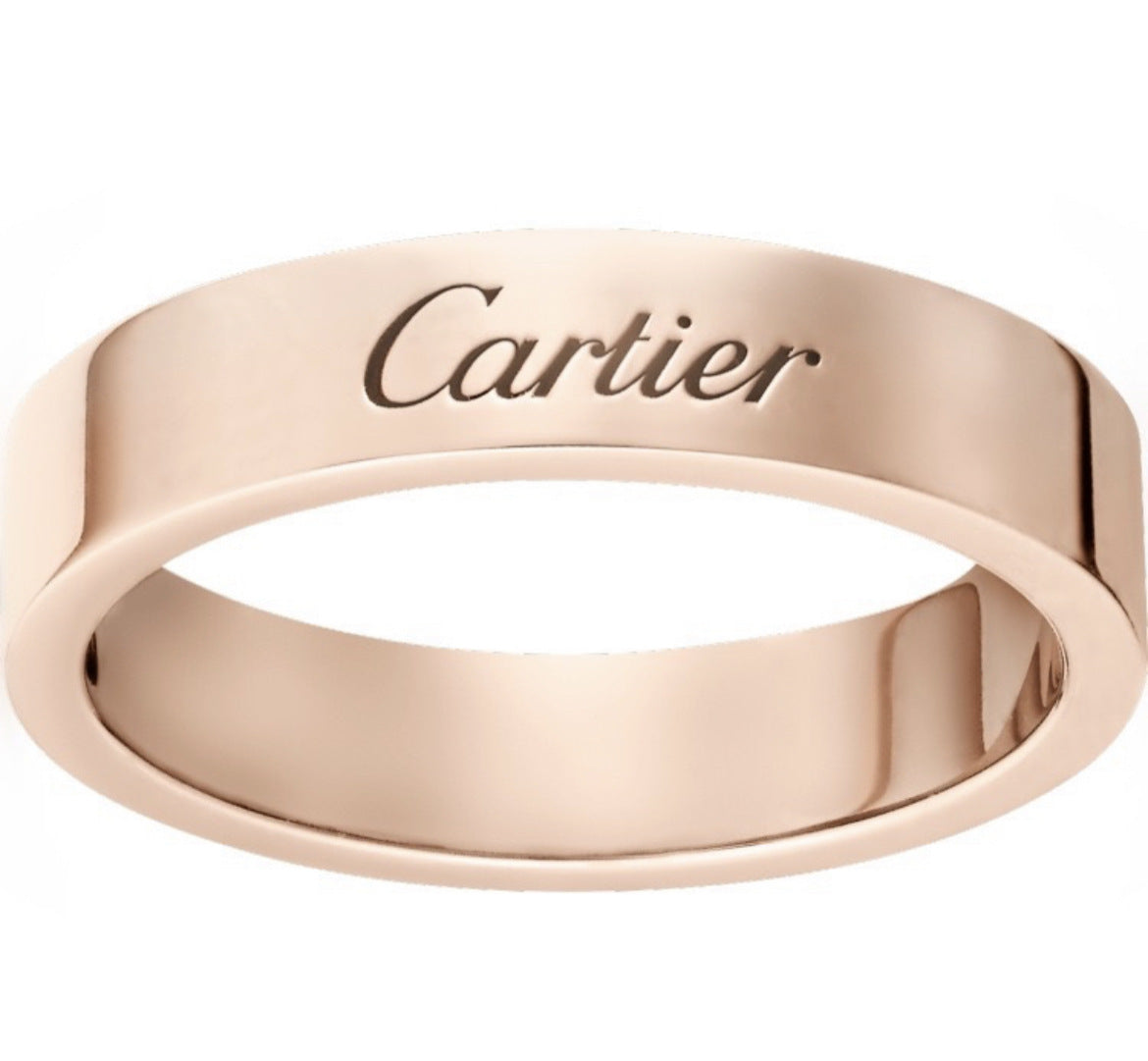 A rose gold Cartier ring with the brand name engraved on the outer band, shown against a plain white background.
