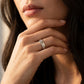 A close-up lifestyle shot of a woman wearing a silver band ring engraved with the name 'Emily' on her finger.