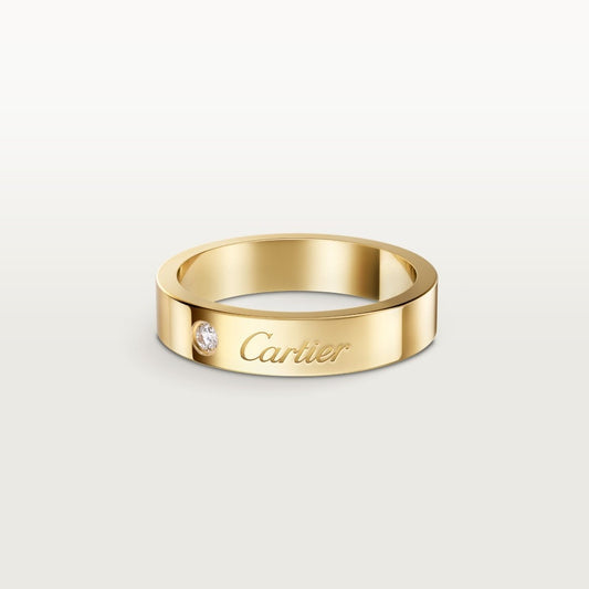 Gold Cartier ring with a diamond on a light gray background