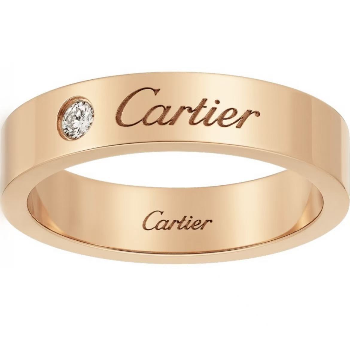 A rose gold Cartier band ring with a single round-cut clear gemstone and engraved Cartier branding on the exterior and interior, shown against a plain white background.