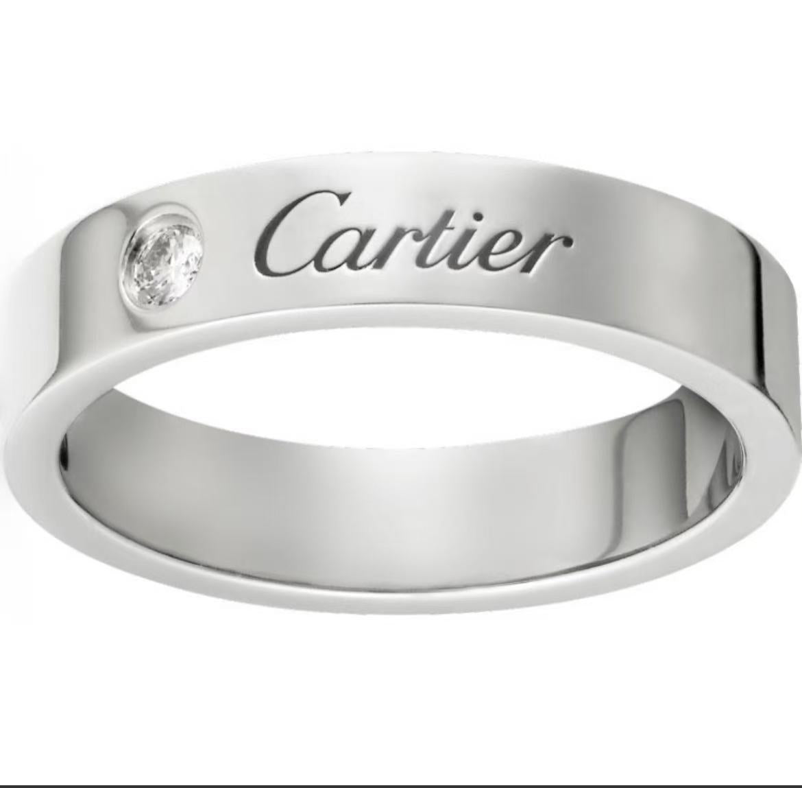 A polished silver-tone Cartier ring with a small round clear gemstone and the Cartier logo engraved on the band, shown against a plain white background.