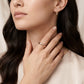 A close-up lifestyle shot of a woman wearing a slim rose gold band ring on her finger and a matching vertical bar earring in her ear, set against a soft beige background.