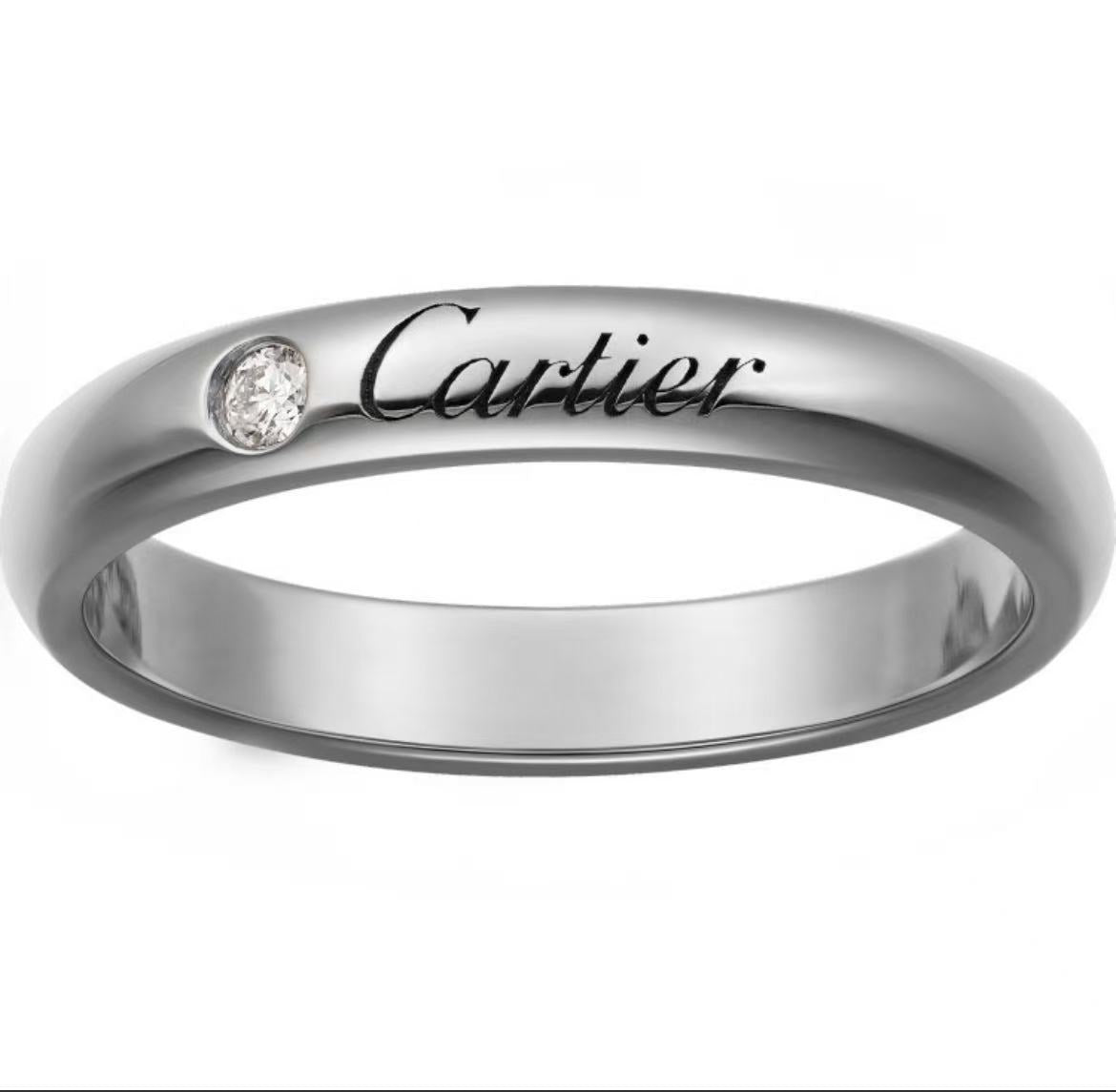 A polished silver-tone Cartier ring with a small round clear gemstone and the Cartier logo engraved on the band, shown against a plain white background.