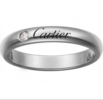 A polished silver-tone Cartier ring with a small round clear gemstone and the Cartier logo engraved on the band, shown against a plain white background.