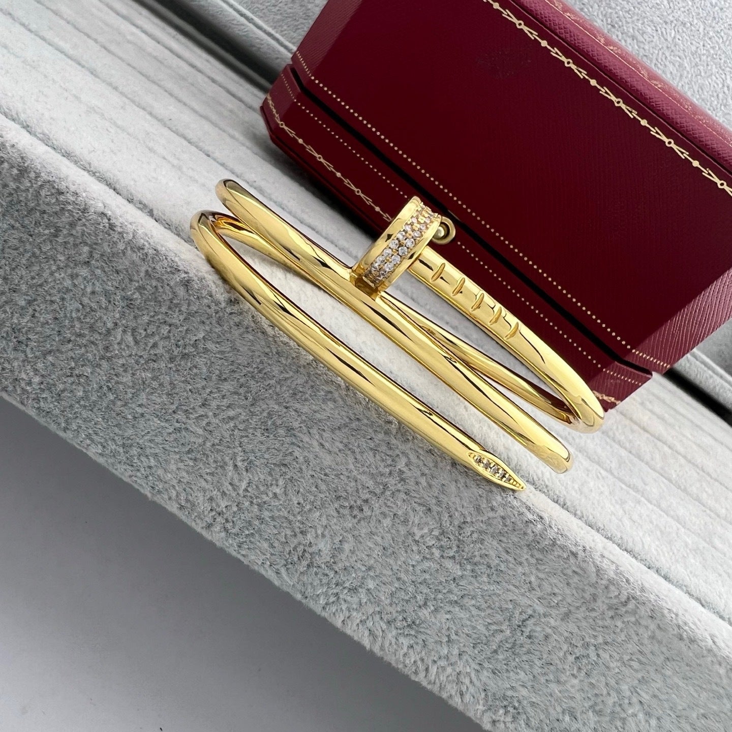 Gold bracelet with a red box on a textured surface
