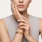Woman wearing gold bracelets on a neutral background