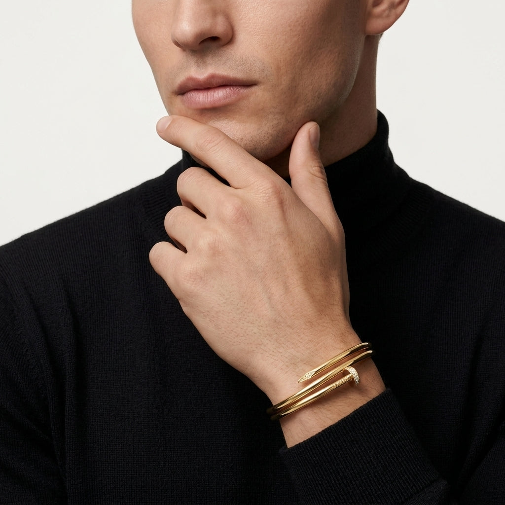 Man wearing a gold bracelet on a plain background