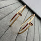 Gold bangles with red gemstones on a textured gray surface
