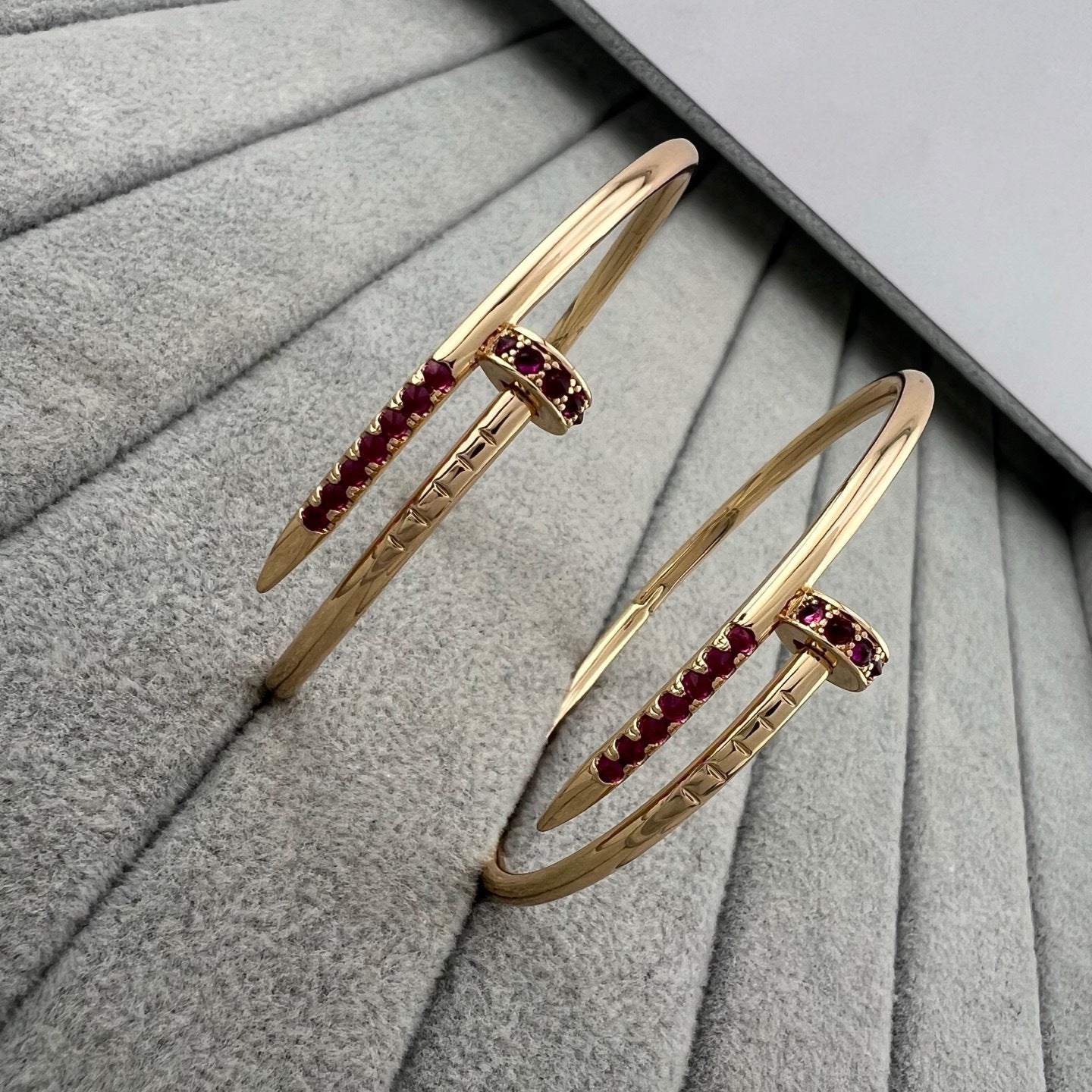 Gold bangles with red gemstones on a textured gray surface