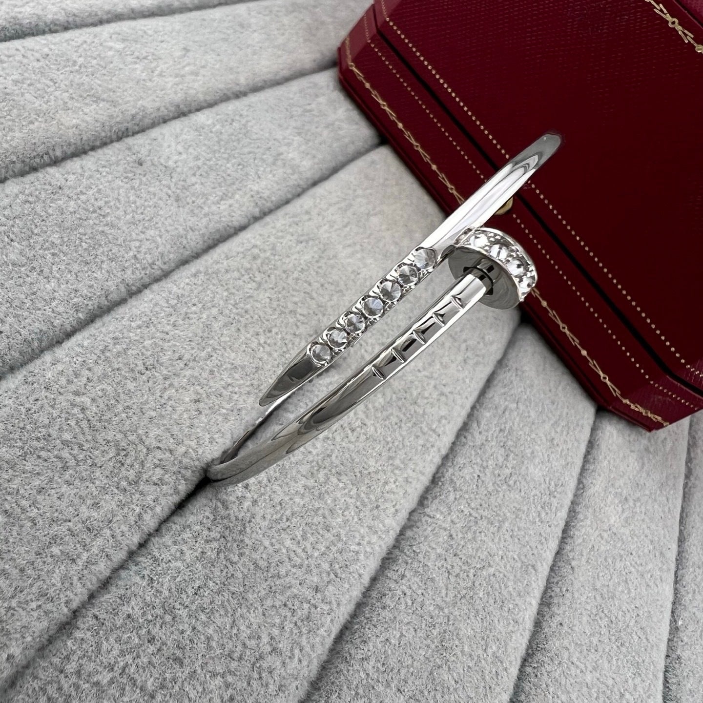 Silver bracelet with gemstones on a gray surface with a red box in the background