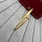 Gold bracelet with crystals on a gray surface with a red handbag in the background