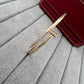 Gold bracelet with crystals on a gray surface next to a red wallet