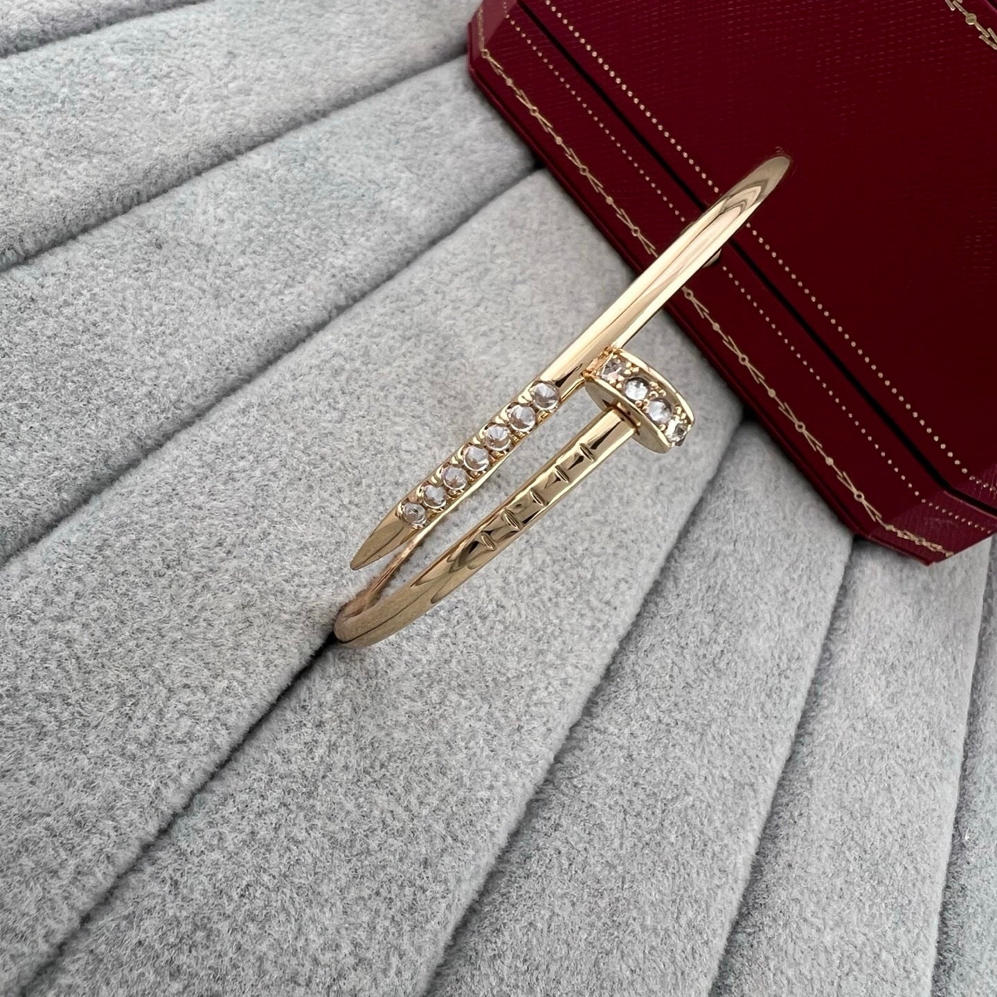 Gold bracelet with crystals on a gray surface next to a red wallet