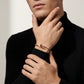 Person wearing a gold bracelet on a plain background