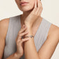 Woman wearing a silver bracelet on her wrist with a neutral background