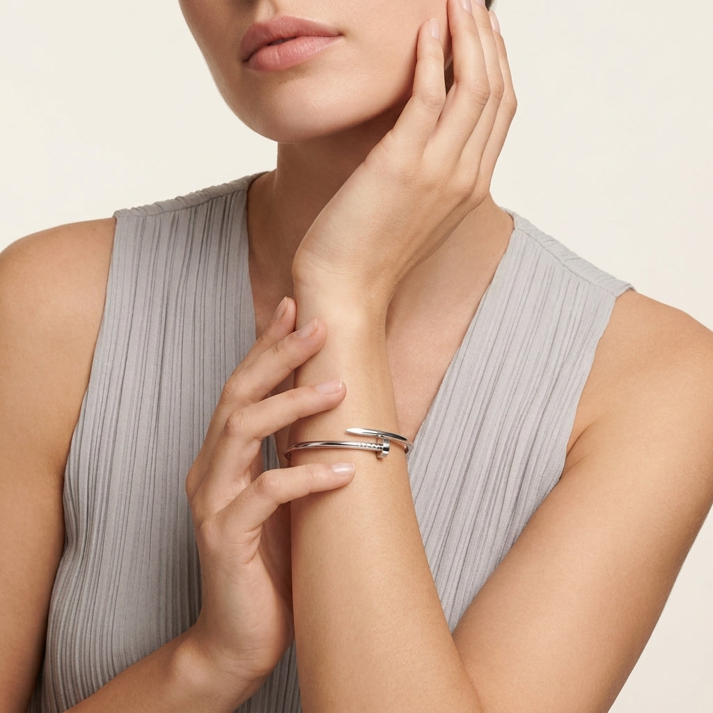 Woman wearing a silver bracelet on her wrist with a neutral background