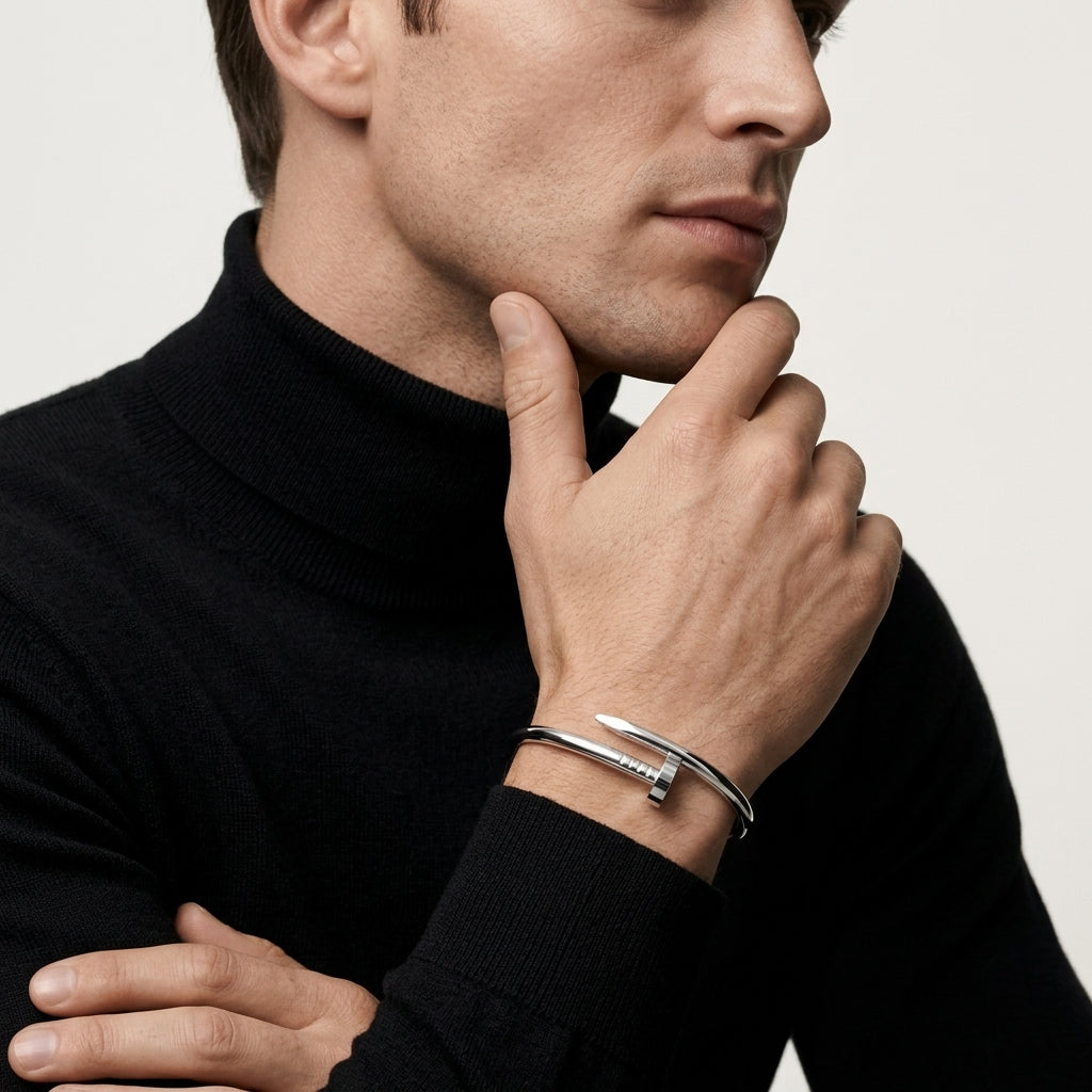 Man wearing a black turtleneck and silver bracelets on a neutral background