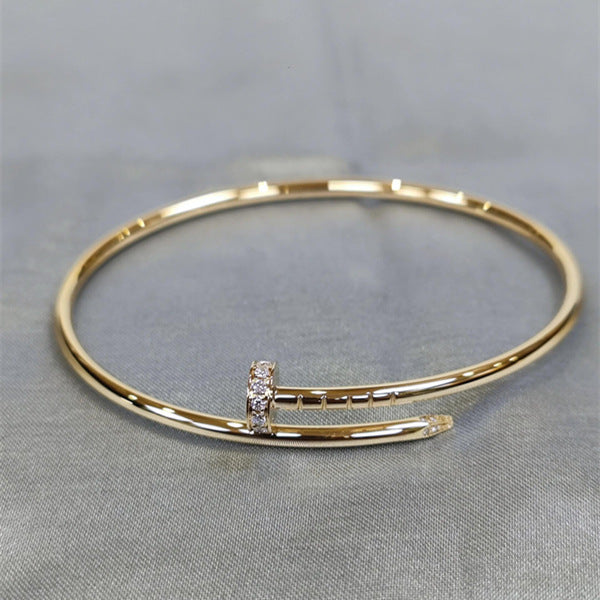 Gold bracelet with a diamond accent on a gray fabric background