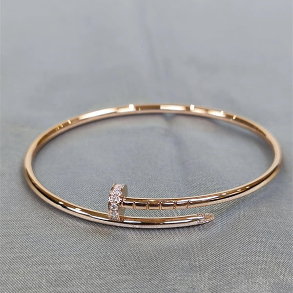 Gold bracelet with a small diamond on a gray background