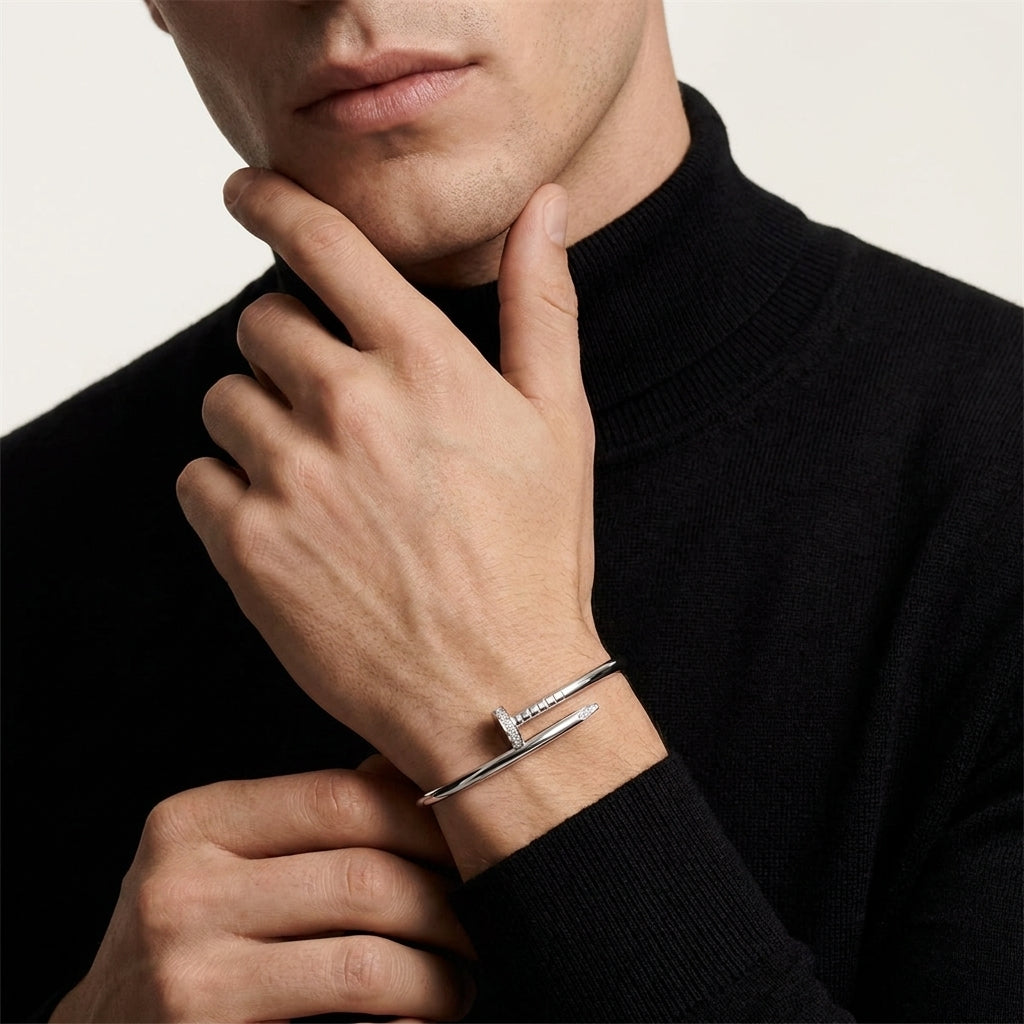 Man wearing a silver bracelet on his wrist with a neutral background