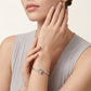 Woman wearing a silver bracelet on her wrist with a neutral background