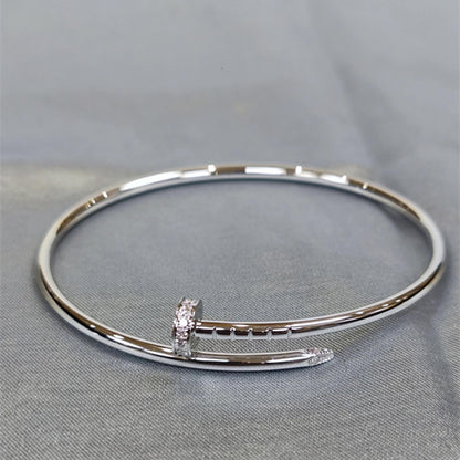 Silver bangle with a small diamond on a gray fabric background