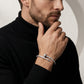 Man wearing a silver bracelet on his wrist, with a neutral background