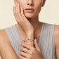 Woman wearing a silver bracelet and ring on a beige background