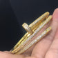 Gold bangles with diamond-like stones on a hand against a black background