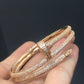 Rose gold bracelet with clear stones on a hand against a dark background