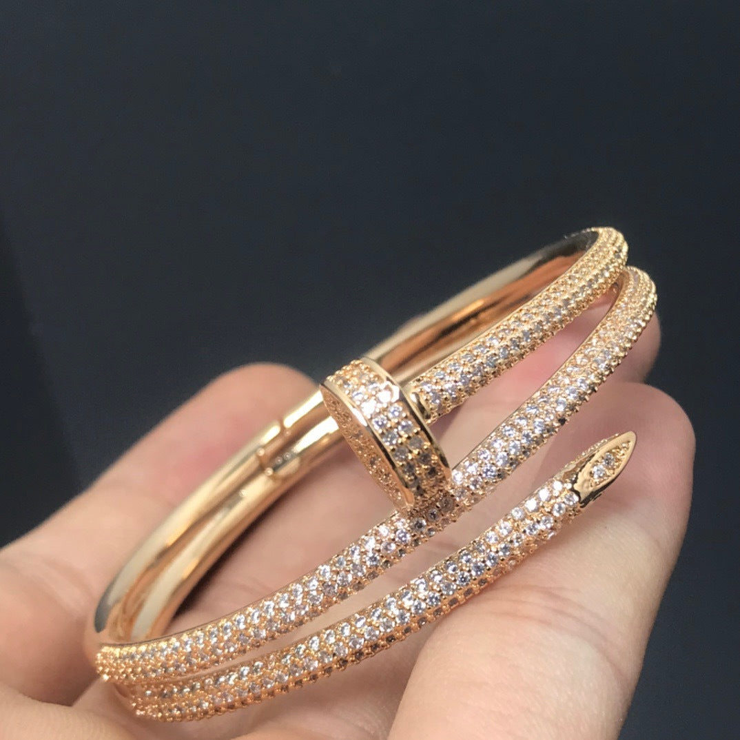 Rose gold bracelet with clear stones on a hand against a dark background