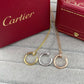 Three Cartier huggie hoop necklaces in gold, silver, and rose gold, displayed on a gray textured surface with red Cartier boxes in the background.