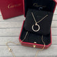A Cartier necklace displayed in an open red Cartier jewelry box on a black cushion, with the matching red box visible behind it. The necklace has a gold-tone chain and a crescent-shaped pendant set with clear stones.
