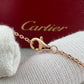 A close-up of a gold-tone Cartier chain with a lobster clasp resting on a white knit surface, with a red Cartier box blurred in the background.