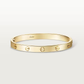 Gold bracelet with Cartier logo on a light beige background