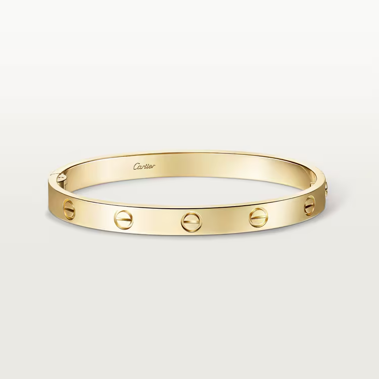 Gold bracelet with Cartier logo on a light beige background