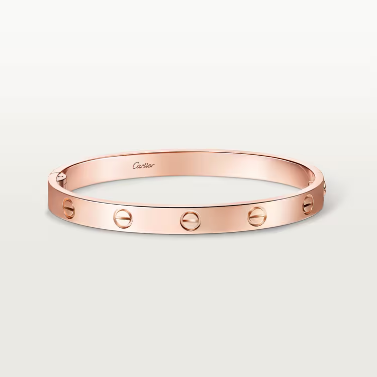 Rose gold bracelet with Cartier logo on a light beige background