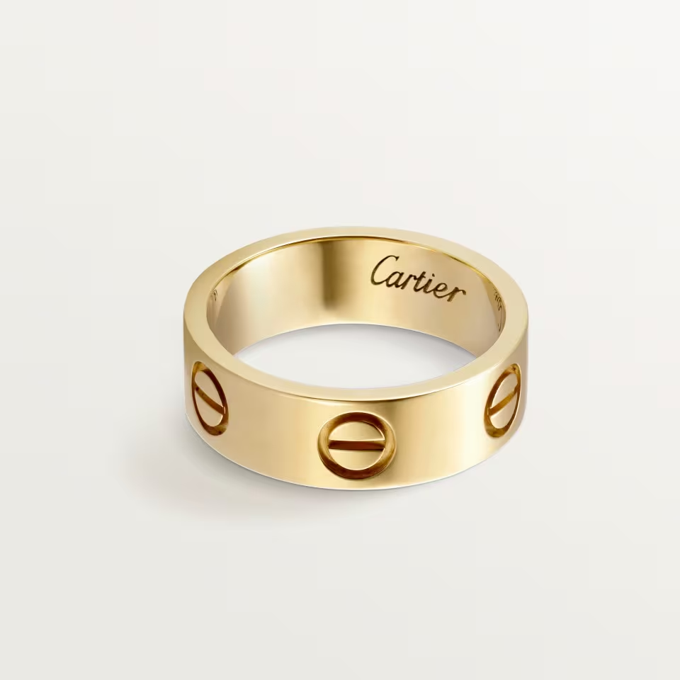 Gold Cartier ring with engraved design on a light gray background