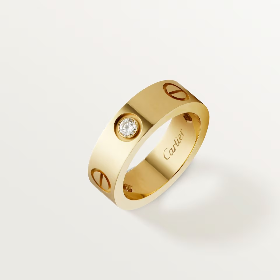 Gold ring with diamond and Cartier logo on a light background