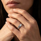 Close-up of a hand wearing a silver ring with a diamond, touching the chin.