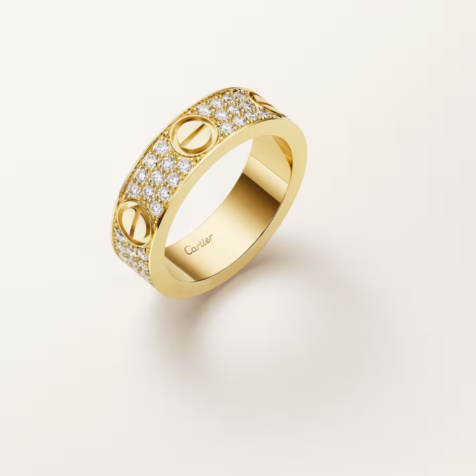 Gold ring with diamond accents on a light beige background