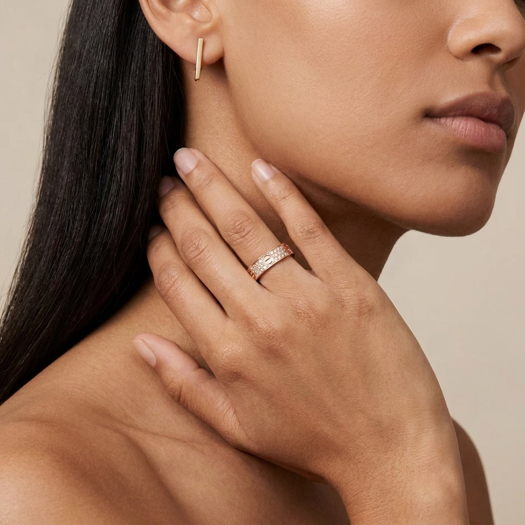 Close-up of a woman wearing a gold earring and ring on a beige background