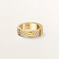 Gold ring with diamond accents on a light beige background