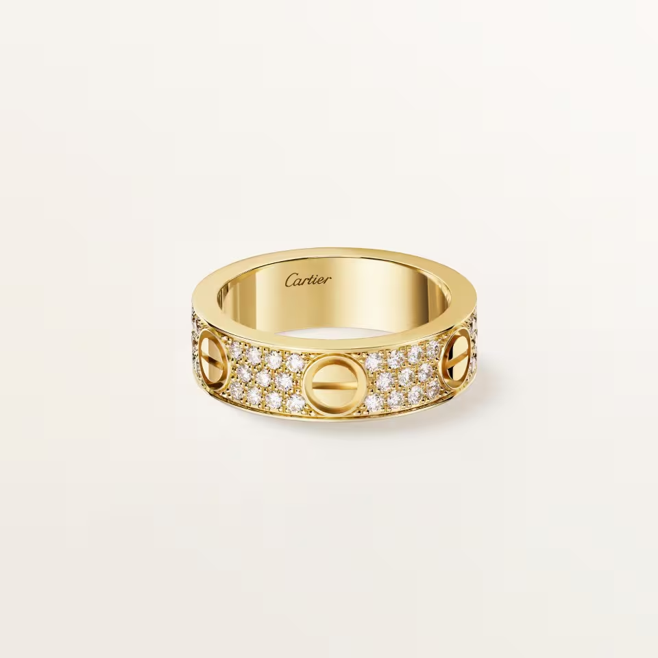 Gold ring with diamond accents on a light beige background